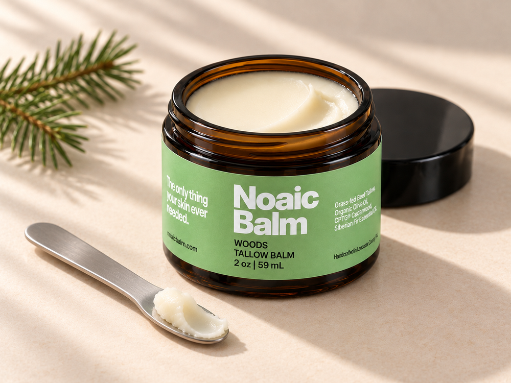 Open Noaic Woods balm jar with dense ivory balm and a small scoop on a cosmetic spatula.